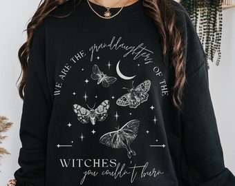 Może przedstawiać: Czarna bluza z białym nadrukiem graficznym przedstawiającym motyle, rosnący księżyc i tekst "We are the granddaughters of the witches you couldn't burn."