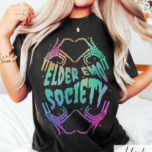 May include: Black t-shirt with a rainbow gradient graphic of two skeleton hands making a heart shape. The text "Elder Emo Society" is inside the heart.