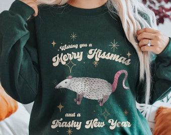 May include: Forest green sweatshirt with a white opossum illustration and the text "Wishing you a Merry Hissmas and a Trashy New Year".