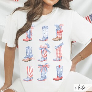 May include: White t-shirt with a design of nine red, white, and blue cowboy boots with stars and bows. The boots are arranged in three rows of three. The shirt has the word "white" printed on the bottom right corner.