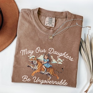 Camisa "Que nuestras hijas sean ingobernables" de Comfort Colors: un regalo feminista de tigre para padres.