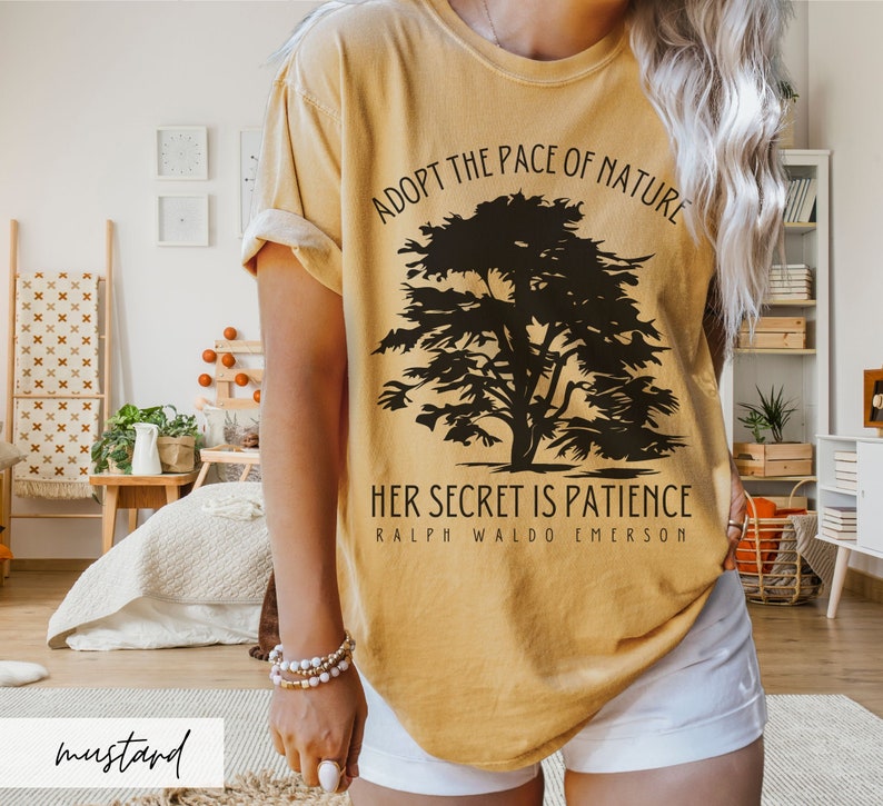 May include: A mustard yellow t-shirt with a black silhouette of a tree and the text "Adopt the pace of nature. Her secret is patience. Ralph Waldo Emerson."