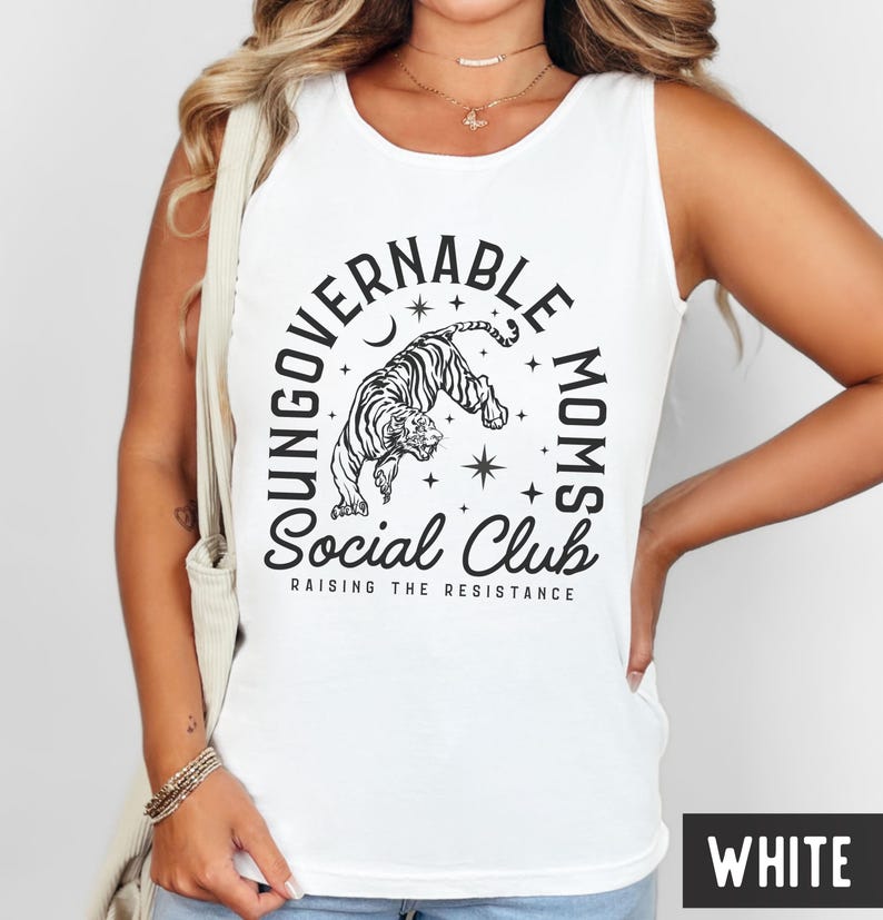 Puede incluir: Camiseta sin mangas blanca con un gr&aacute;fico en blanco y negro. El gr&aacute;fico presenta un tigre, estrellas y las palabras "UNGOVERNABLE MOMS Social Club" y "RAISING THE RESISTANCE". La camiseta sin mangas es sin mangas.