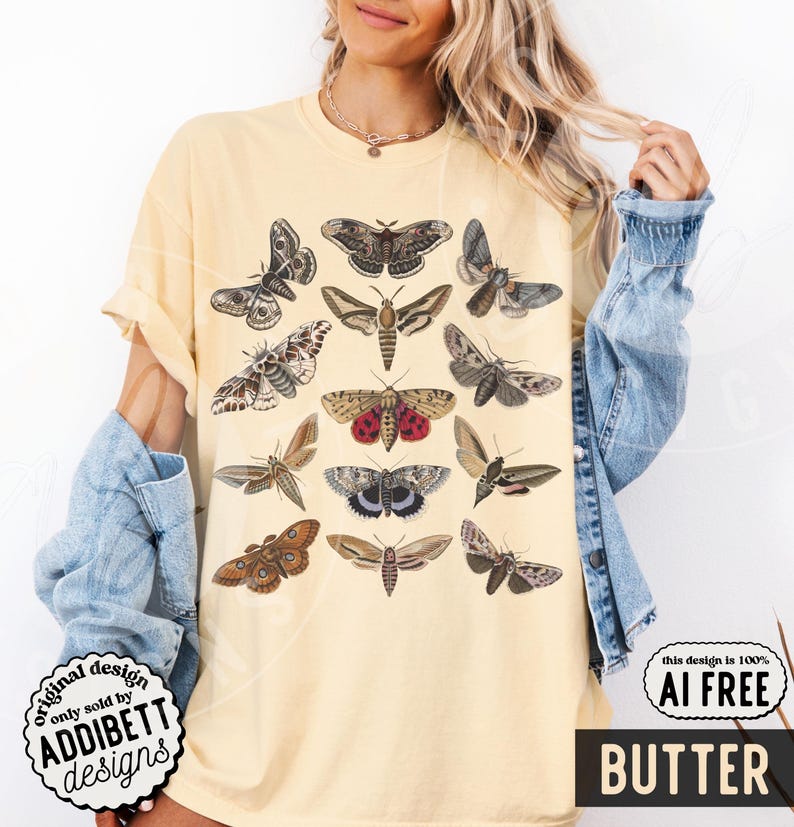 May include: A pale yellow short-sleeve t-shirt featuring a graphic print of various moth species in shades of brown, gray, and red. The design displays twelve distinct moth illustrations arranged in a grid pattern across the front of the garment.