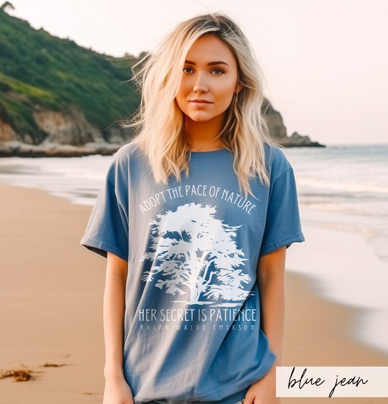 May include: A blue t-shirt with a white graphic of a tree and the text "Adopt the pace of nature. Her secret is patience. Ralph Waldo Emerson."