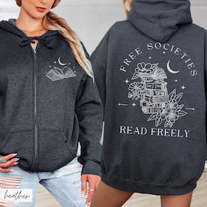 May include: Dark heather gray zip-up hoodie with a white graphic of an open book, moon, and stars on the front. The back features the text "FREE SOCIETIES READ FREELY" with a stack of books, flowers, and a crescent moon.