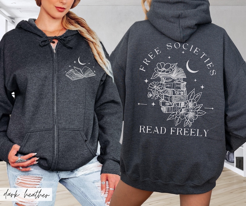 May include: Dark heather gray zip-up hoodie with a white graphic of an open book, moon, and stars on the front. The back features the text "FREE SOCIETIES READ FREELY" with a stack of books, flowers, and a crescent moon.