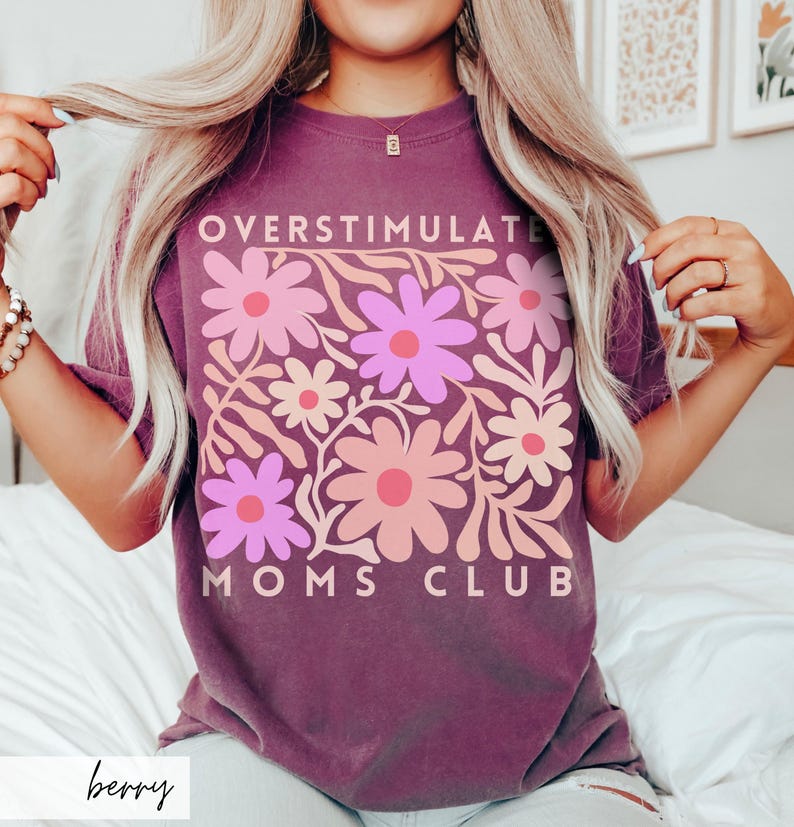 May include: A purple t-shirt with a floral design and the text "Overstimulate Moms Club".