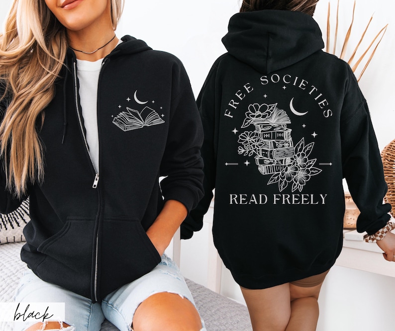 May include: Black zip-up hoodie with a white graphic of an open book and crescent moon on the front. The back features the text "FREE SOCIETIES READ FREELY" with a stack of books, flowers, and a crescent moon design. A casual, comfortable garment.