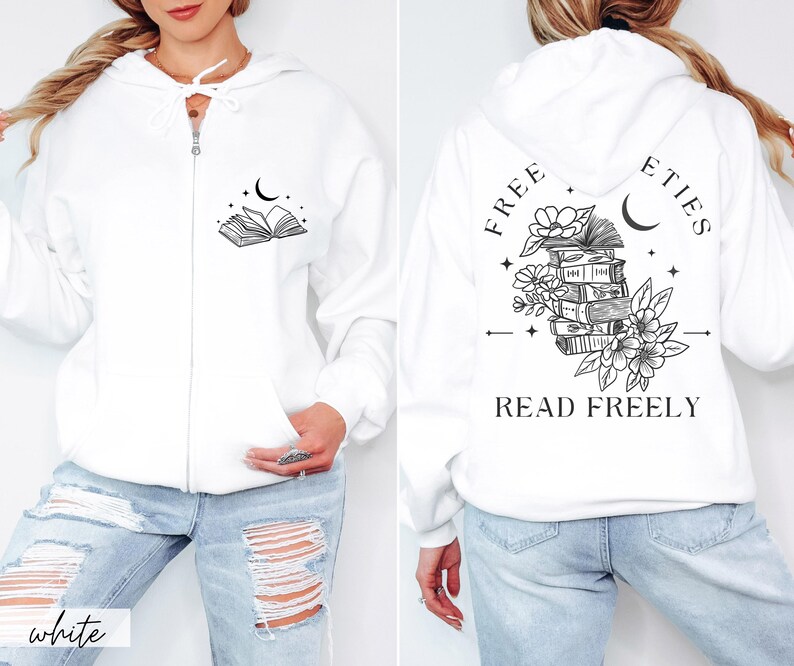 May include: White zip-up hoodie with a hood and front pockets. The front features a black graphic of an open book, a crescent moon, and stars. The back displays a stack of books, flowers, and the text "FREE ETIES READ FREELY".