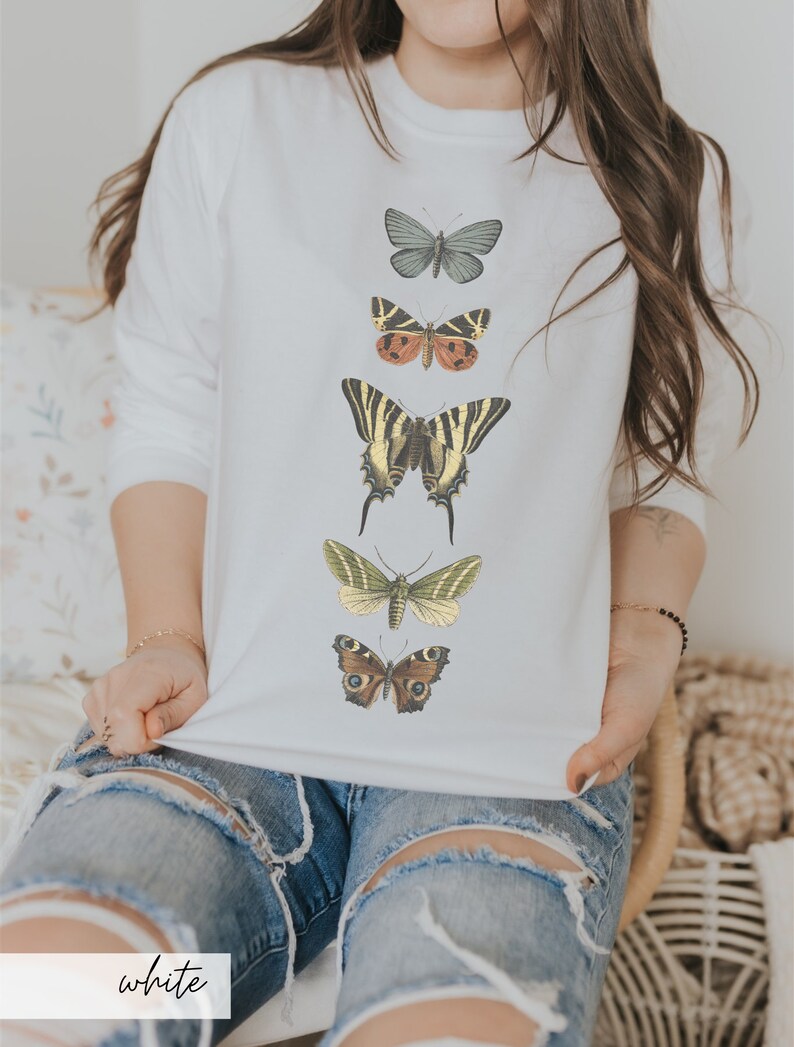 May include: White sweatshirt with a vertical row of five different colored butterflies printed on the front. The butterflies are in various shades of brown, green, yellow, and black.