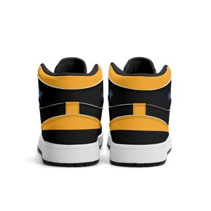 Peut inclure: Paire de baskets montantes noires, jaunes et blanches. Le design comprend un col, un talon et une languette jaunes, avec une semelle blanche. De petits losanges bleus sont visibles sur les c&ocirc;t&eacute;s. Chaussures de sport.