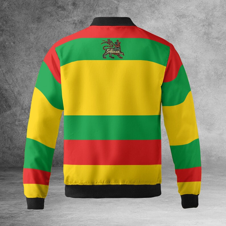 May include: A yellow, green, and red striped bomber jacket with a black collar and cuffs. The jacket features a lion emblem with the text "Selassie" on the back.