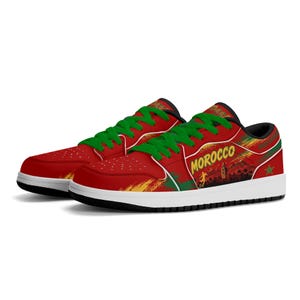 May include: Low-top sneakers in red, green, and yellow with white soles. The side features the text MOROCCO, a silhouette of a soccer player, and a green star. The design includes brushstroke patterns and green laces with black interior lining.