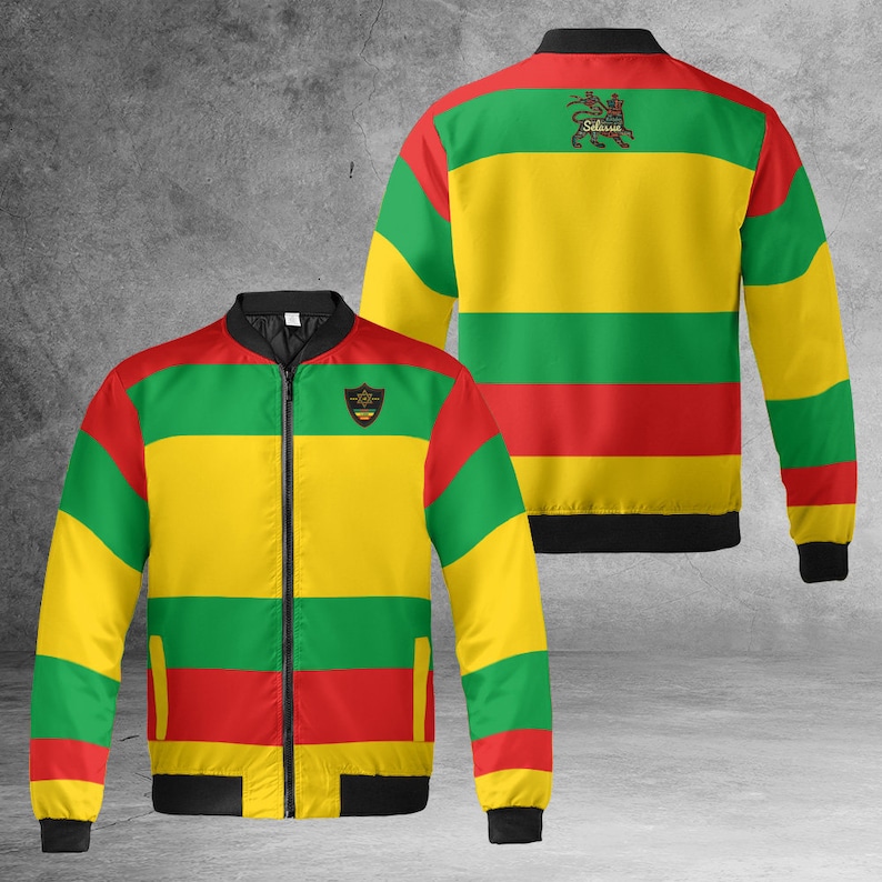 May include: A yellow, green, and red striped bomber jacket with a black zipper and black cuffs. The jacket has a small patch on the left chest with a lion and the word "Selassie".