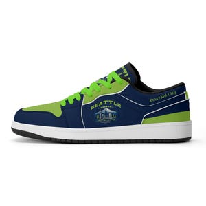 Puede incluir: Una zapatilla baja en azul marino y verde lima con cordones verde lima. El lateral presenta un gráfico del horizonte de Seattle y un balón de fútbol americano con el texto SEATTLE. El talón incluye el texto Emerald City en letras verdes.