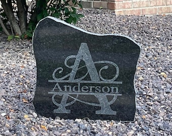 May include: A black granite rock with a personalized engraved design. The design features a large letter "A" with a decorative flourish and the name "Anderson" written below it.