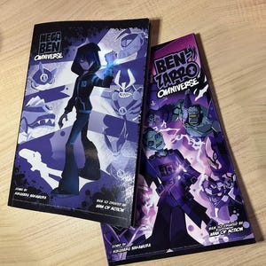 May include: Two comic books with covers in shades of purple and black, featuring characters from the Ben 10 animated series. The covers display illustrations of characters in action poses. The titles read "Mega Ben Omniverse" and "Ben Zarro Omniverse".