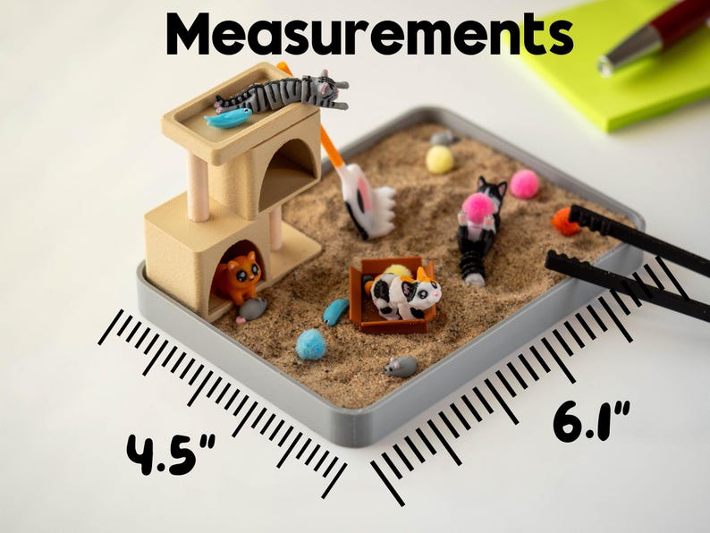 May include: A miniature cat-themed sandbox with a beige cat tower, sand, and various cat figurines. The sandbox measures 4.5 inches by 6.1 inches. Includes a small rake and tweezers.