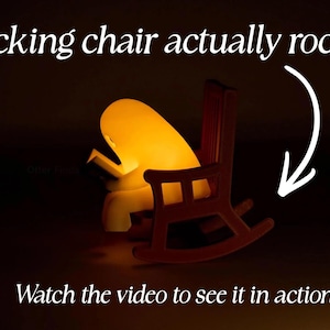 Side view of a glowing reading ghost in a brown rocking chair, with a curved arrow beside the rockers. Text reads: Rocking chair actually rocks! Watch the video to see it in action!