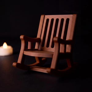 Brown miniature rocking chair shown without the ghost, with a tall slatted back, armrests and curved rockers. A glowing LED tealight sits separately in the background.