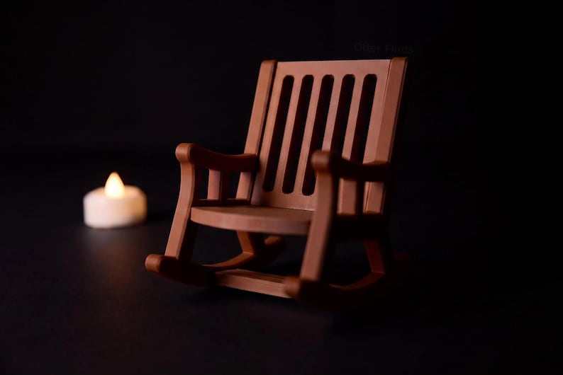 Brown miniature rocking chair shown without the ghost, with a tall slatted back, armrests and curved rockers. A glowing LED tealight sits separately in the background.
