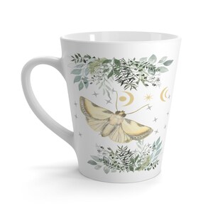 May include: White ceramic latte mug with a watercolor design of a moth, leaves, and gold crescent moons and stars.