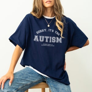 K&ouml;nnte beinhalten: Ein marineblaues T-Shirt mit dem Aufdruck "Sorry, it's the Autism Constantly Overstimulated" in wei&szlig;.