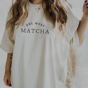May include: A white oversized t-shirt with the text "ONE MORE MATCHA" printed on the front.