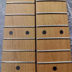 May include: Two unfinished wooden guitar necks with black dot inlays and silver fret lines.