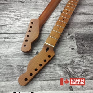 Könnte beinhalten: Zwei unfertige Holzhals für Gitarren, einer mit Bünden und der andere ohne. Die Hälse sind hellbraun mit vorgebohrten Löchern für Stimmwirbel. Das Bild enthält den Text "Made in Canada" und das Havok-Logo.
