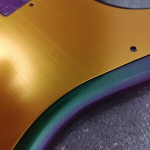 May include: A gold electric guitar body with a brushed metal finish. The body is partially painted with a purple, green, and blue iridescent paint.
