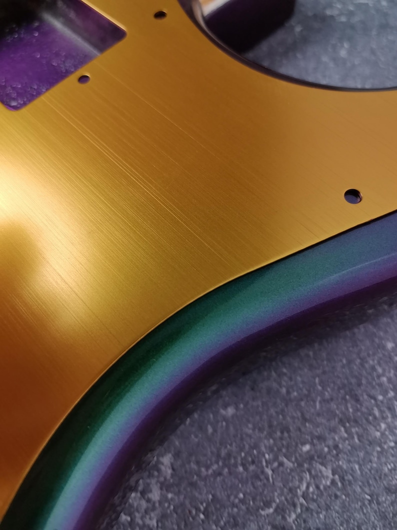 May include: A gold electric guitar body with a brushed metal finish. The body is partially painted with a purple, green, and blue iridescent paint.
