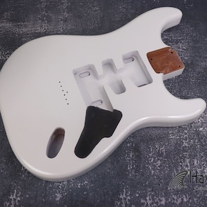 May include: A white electric guitar body with cut-out sections for pickups and electronics. The body has a smooth, glossy finish, ready for assembly. The brand name "Havok" is visible at the bottom right.
