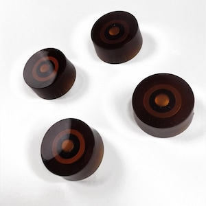 Peut inclure: Quatre boutons de guitare bruns avec un motif de cercles concentriques d'une couleur brun foncé.