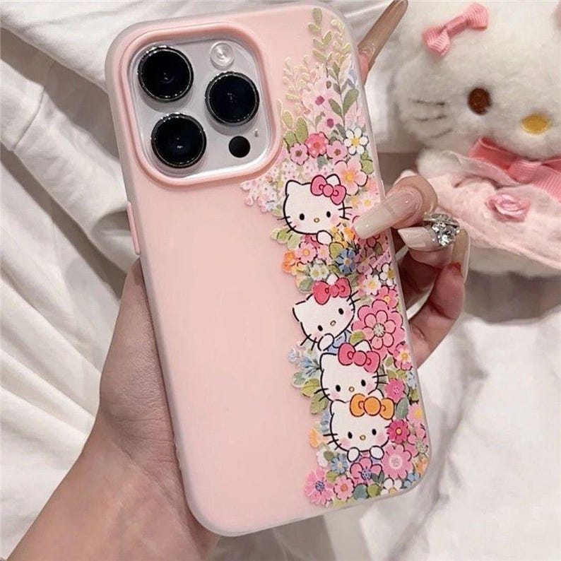 Puede incluir: Funda de tel&eacute;fono rosa con personajes de Hello Kitty y detalles florales. La funda tiene un borde transparente y presenta a Hello Kitty con lazos rosas, rodeada de flores coloridas. Dise&ntilde;ada para un smartphone.