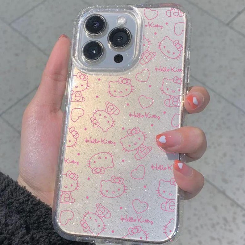 K&ouml;nnte beinhalten: Transparente Handyh&uuml;lle mit einem rosa Hello Kitty Muster und Herzen. Die H&uuml;lle hat einen glitzernden Hintergrund und die Worte "Hello Kitty" sind aufgedruckt. Die Handyh&uuml;lle ist f&uuml;r ein Smartphone konzipiert.