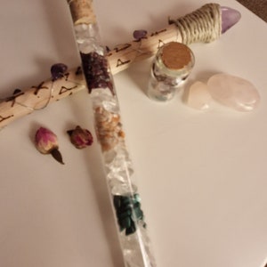 Könnte beinhalten: Ein Glas-Reagenzglas gefüllt mit klaren Quarzkristallen, Amethyst, Rosenquarz und grünen Aventurinkristallen. Das Reagenzglas hat einen Korkstopfen und steht auf einer weißen Oberfläche.