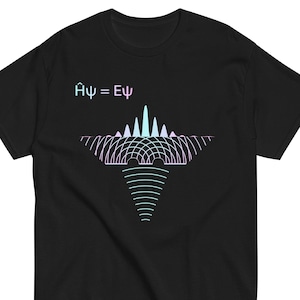 以下が含まれることがあります： 黒いTシャツ。Âψ = Eψ の数式が青と紫のグラデーションで描かれています。数式の下には、同じ色調の波模様が描かれています。このTシャツは、クルーネックの半袖です。