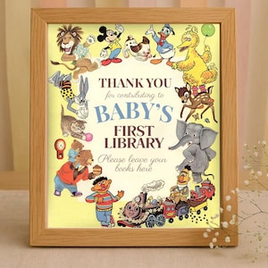 以下が含まれることがあります： 木製のフレーム入りプリント。背景は黄色で、「THANK YOU for contributing to BABY'S FIRST LIBRARY」の文字が書かれています。ミッキーマウスやバッグス・バニーなど、漫画のキャラクターに囲まれています。下部には列車があります。