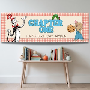 May include: A birthday banner featuring illustrations of characters from a children's book. The banner has a light beige background with the words "CHAPTER ONE" and "HAPPY BIRTHDAY JAYDEN" in blue text. The banner is framed with a red and white checkered pattern.