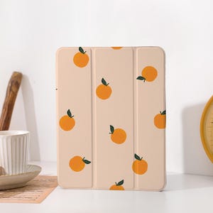 May include: A light pink iPad case with a repeating pattern of orange fruit with green leaves.