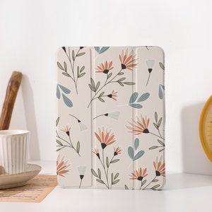 Puede incluir: Una funda para tablet blanca con un patrón floral con flores y hojas de color naranja, rosa y azul. La funda está hecha de un material suave y duradero y está diseñada para proteger tu tablet de arañazos y golpes.