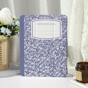 Puede incluir: Un cuaderno de composición con una cubierta moteada morada y blanca. La cubierta tiene una etiqueta rectangular con las palabras "COMPOSITION BOOK" y líneas en blanco. El lomo es de color morado liso. El cuaderno está sobre una superficie blanca.
