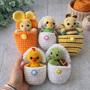 Pode incluir: Uma coleção de brinquedos de animais de crochê feitos à mão, incluindo um coelho em uma cenoura, um pássaro, uma abelha, um pintinho e uma tartaruga, cada um aninhado em um ovo de crochê. Os brinquedos são em várias cores, como amarelo, laranja, branco e verde.