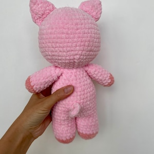 Op de afbeelding: Een roze gehaakt knuffelvarken met een gekrulde staart.