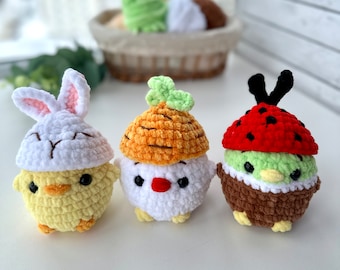 May include: Three crocheted amigurumi toys shaped like chicks. One chick is wearing a white bunny hat, another is wearing a brown and orange carrot hat, and the third is wearing a red and green ladybug hat.