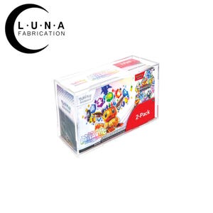 May include: A clear acrylic display case holding a 2-pack of Pokemon Prismatic Evolution Elite Trainer Box. The box features colorful graphics of Pokemon characters and gemstones. The case has the Luna Fabrication logo.