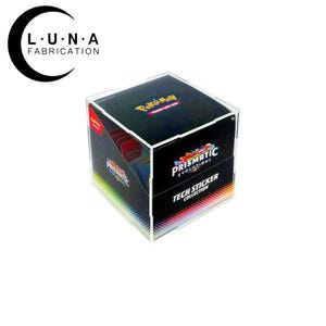 May include: A clear acrylic display case for a trading card collection. The case features a black top and front panel with the "Pokemon Trading Card Game" logo and "Prismatic Evolutions Tech Sticker Collection" text. The case has a rainbow-colored bottom.