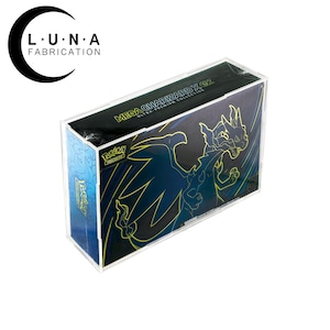 May include: A clear acrylic display case encasing a Pokemon Mega Charizard EX Ultra Premium Collection box. The box features a black and blue design with a yellow Charizard illustration. The case is designed to protect and showcase the collectible.